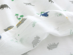 Close-up of breathable slub cotton fabric with cartoon dinosaur print on a white baby tee
