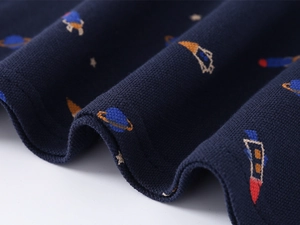 Macro view of navy blue cotton polo shirt fabric with colorful rocket and planet prints