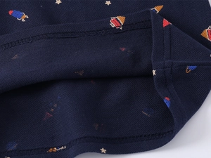 Close-up of navy pique cotton fabric with colorful rocket and star patterns on polo shirt