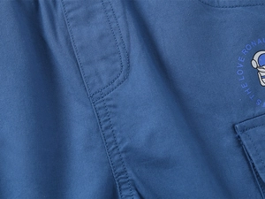 Detailed view of boys' blue cotton twill shorts with astronaut print and pocket stitching