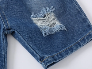 Detail of distressed blue denim shorts showing ripped texture and contrast stitching