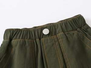 Detail of army green shorts with elastic waist, metal button and orange contrast stitching