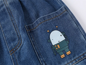 Close-up of boys denim shorts featuring a cute cartoon robot print and yellow stitching