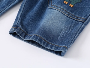 Detail of kids denim shorts featuring washed blue fabric with cartoon robot embroidery