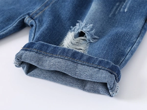 Detailed close-up of blue denim boy's shorts featuring frayed edges and rolled-up hem texture