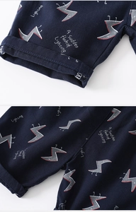 Close-up of navy cotton fabric with geometric lightning print and cuffed hem on boys shorts