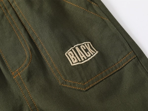 Close-up of military green cargo shorts with orange stitching and BLACK embroidered patch