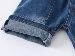 Close-up of boys denim shorts cuff with yellow double stitching and rolled hem detail