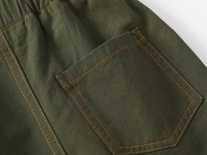 Detailed macro view of army green cotton twill shorts with elastic waistband and pocket seams