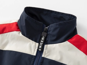 Detail of color-block boys' jacket showing standing collar and branded zipper pull