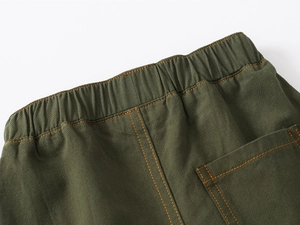 Detail of olive green kids shorts showing elastic waistband and contrast orange stitching