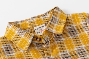 Gros plan du col de chemise à carreaux pour enfant avec tissu sergé et boutons ambrés