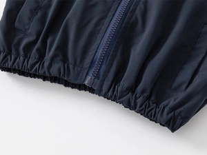 Detail of dark blue boys' jacket with plastic zipper and elastic hem on white background