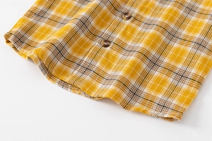 Détail de l'ourlet d'une chemise à carreaux jaunes avec boutons marbrés et tissu doux