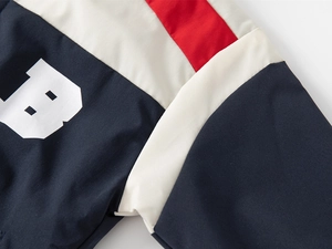Detail of color-block jacket with navy, white, red fabric and large letter B print