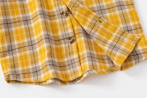 Gros plan détaillé du tissu à carreaux jaune, texture brossée et boutons foncés style bois