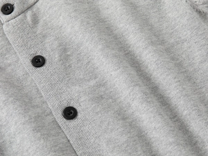 Dettaglio del cardigan in maglia grigia con bottoni neri lisci e trama fine