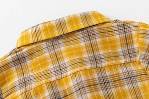 Détail d'une chemise à carreaux jaunes montrant le col carré et les coutures soignées