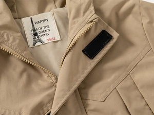 Detailed close-up of zipper and velcro closure on khaki hooded children's windbreaker