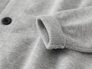 Dettaglio dei polsini a costine e della trama a maglia fine del cardigan grigio bimbo