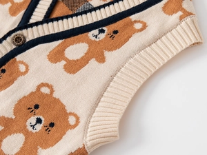 Close-up of knit vest featuring brown cartoon bear pattern and dark wood button