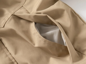 Close-up of a khaki hooded jacket showing high-quality twill fabric and pocket detail