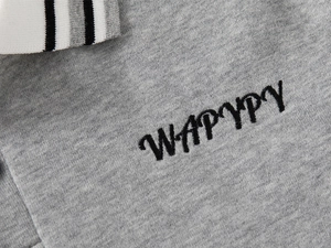 Détail du col polo à rayures grises avec broderie WAPYPY précise sur le tissu