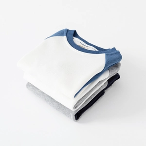 Three neatly folded color-block children's sweatshirts with ribbed crewnecks in white and blue