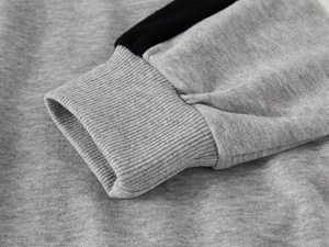 Gros plan des poignets en tricot gris avec rayures noires sur un sweat polo pour enfant