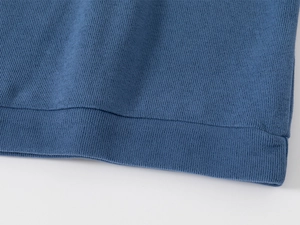 Detailed macro view of the ribbed hem and texture of a blue knitted cotton sweater