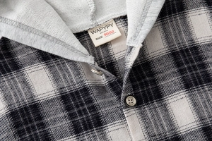 Detail view of cotton plaid shirt neckline with drawstring hood and branded buttons