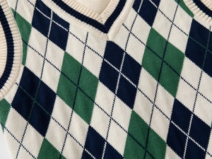 Dettaglio del gilet in maglia a rombi con scollo a V e finiture a costine