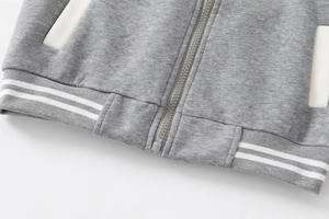 Dettaglio della giacca in maglia grigia per bambini con bordo a coste e zip bianca