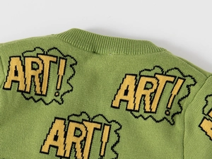Detail of green knitted sweater featuring a ribbed neckline and pop art embroidery