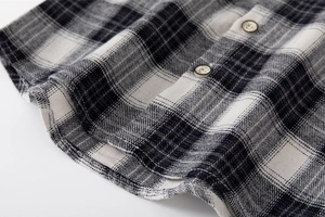 Detailed close-up of woven black and white plaid fabric texture with beige resin buttons
