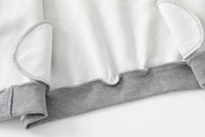 Dettaglio dell'orlo in maglia grigia e fodera in pile bianco di giacca da baseball bambino