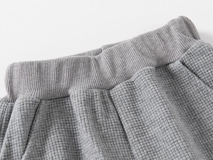 Détail du tissu gaufré gris clair et de la taille élastique côtelée du pantalon garçon