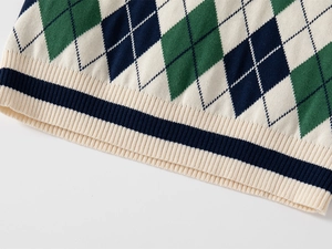 Dettaglio del gilet in maglia per bambini con motivo a rombi verdi e bordo inferiore a coste