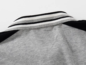 Détail d'un polo gris avec col en maille rayée et texture de manches raglan
