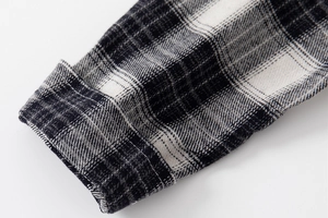 Detailed macro view of the black and white plaid shirt cuff showing high-quality stitching