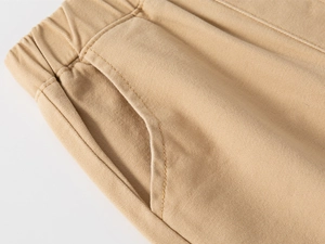 Dettaglio dei pantaloni in cotone kaki con vita elastica e cuciture delle tasche laterali