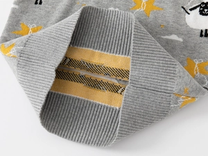 Close-up of grey knit sweater showing cartoon sheep, yellow star, and ribbed cuff texture