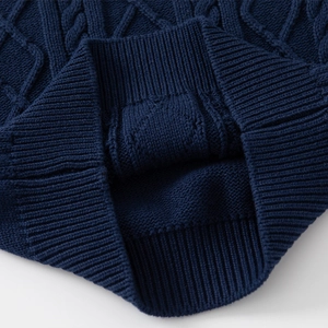 Detail view of navy blue cable knit fabric and ribbed cuff on a children's sweater