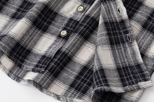 Macro detail of black and white plaid flannel shirt fabric with engraved classic button