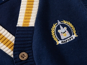 Macro shot of navy knit cardigan featuring embroidery bear badge and wooden button detail