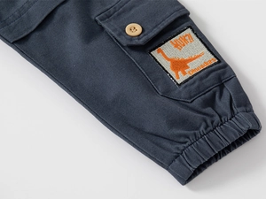 Détail du pantalon cargo enfant bleu marine avec écusson dinosaure et cheville élastique