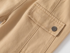 Dettaglio macro dei pantaloni cargo kaki con tasca a patta e bottone in metallo scuro