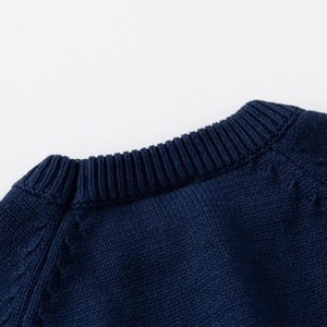 Detail of dark blue cable knit sweater featuring a ribbed neckline and textured pattern