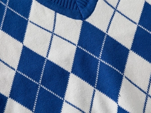 Macro shot of V-neck knitted vest with classic blue and white argyle jacquard pattern