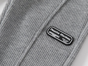 Détail de maille gaufrée grise avec un écusson logo rectangulaire en caoutchouc noir